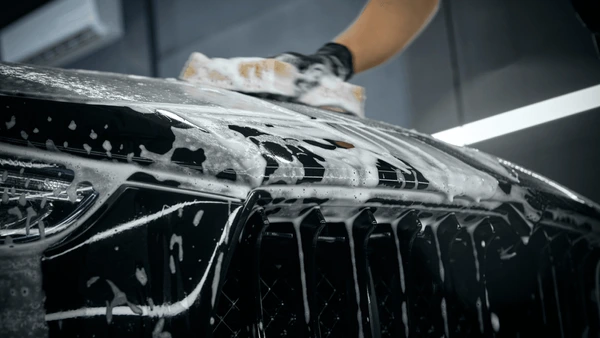 Hand-washing luxury vehicle hood with foam